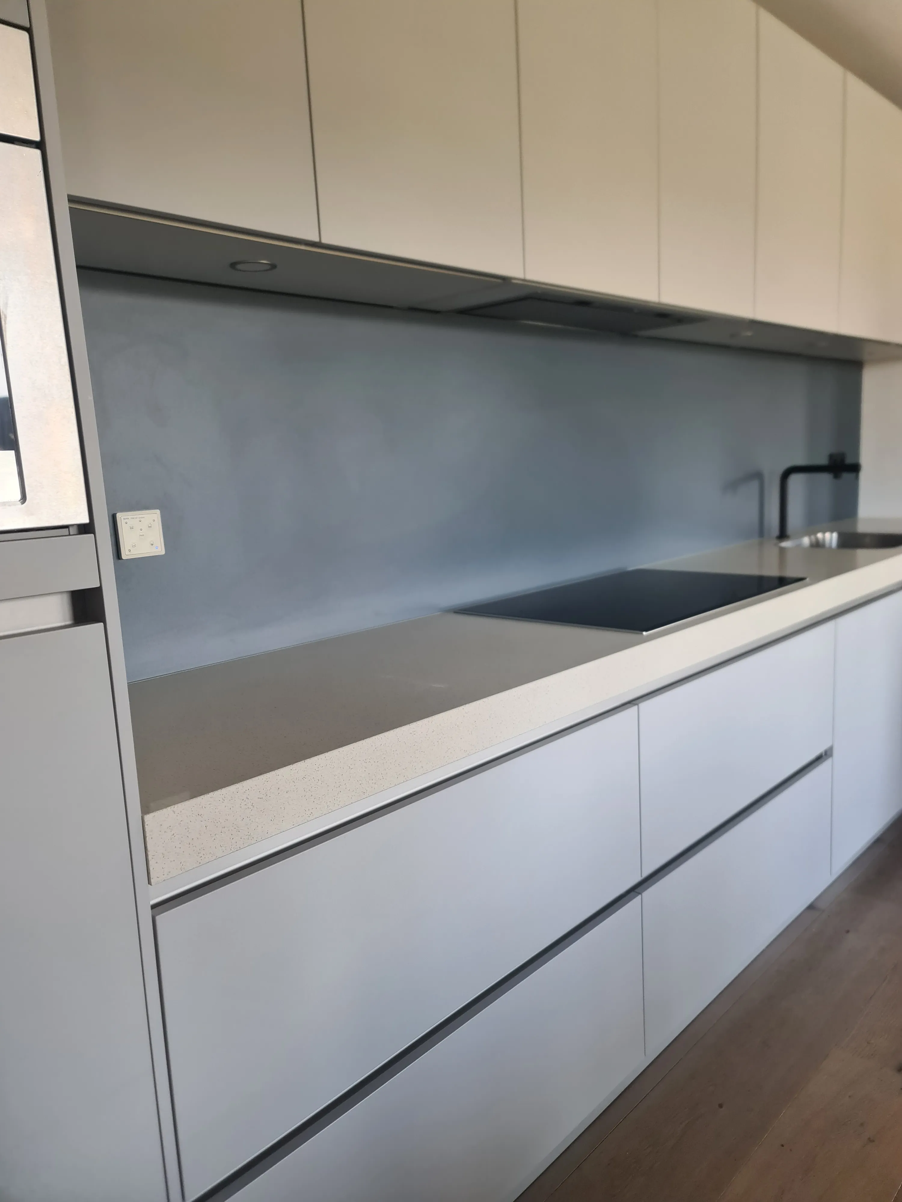 Lichte keuken met een lange naadloze blauwe rugwand op maat