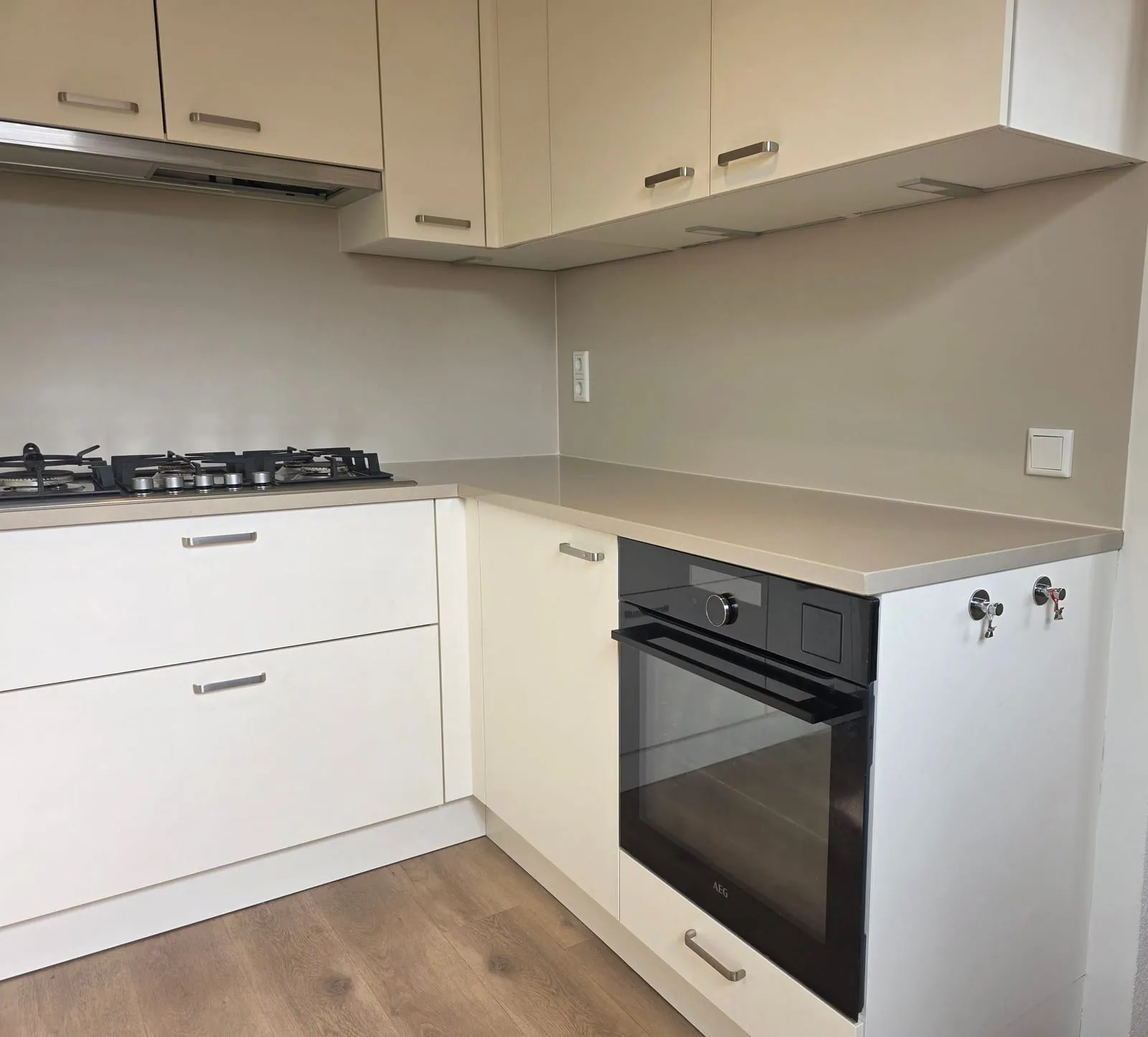 Witte hoogglanskeuken met een naadloze greige Steel Magnetic rugwand