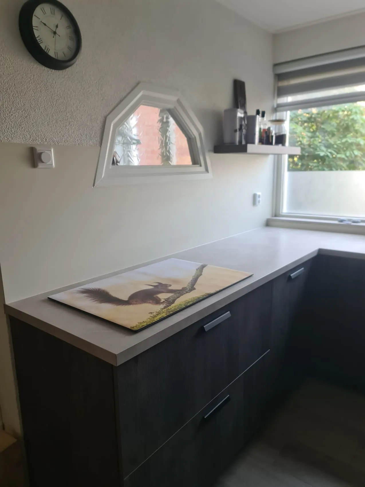 Keuken met een bijzonder hoekig raam en een naadloze crèmekleurige rugwand op maat