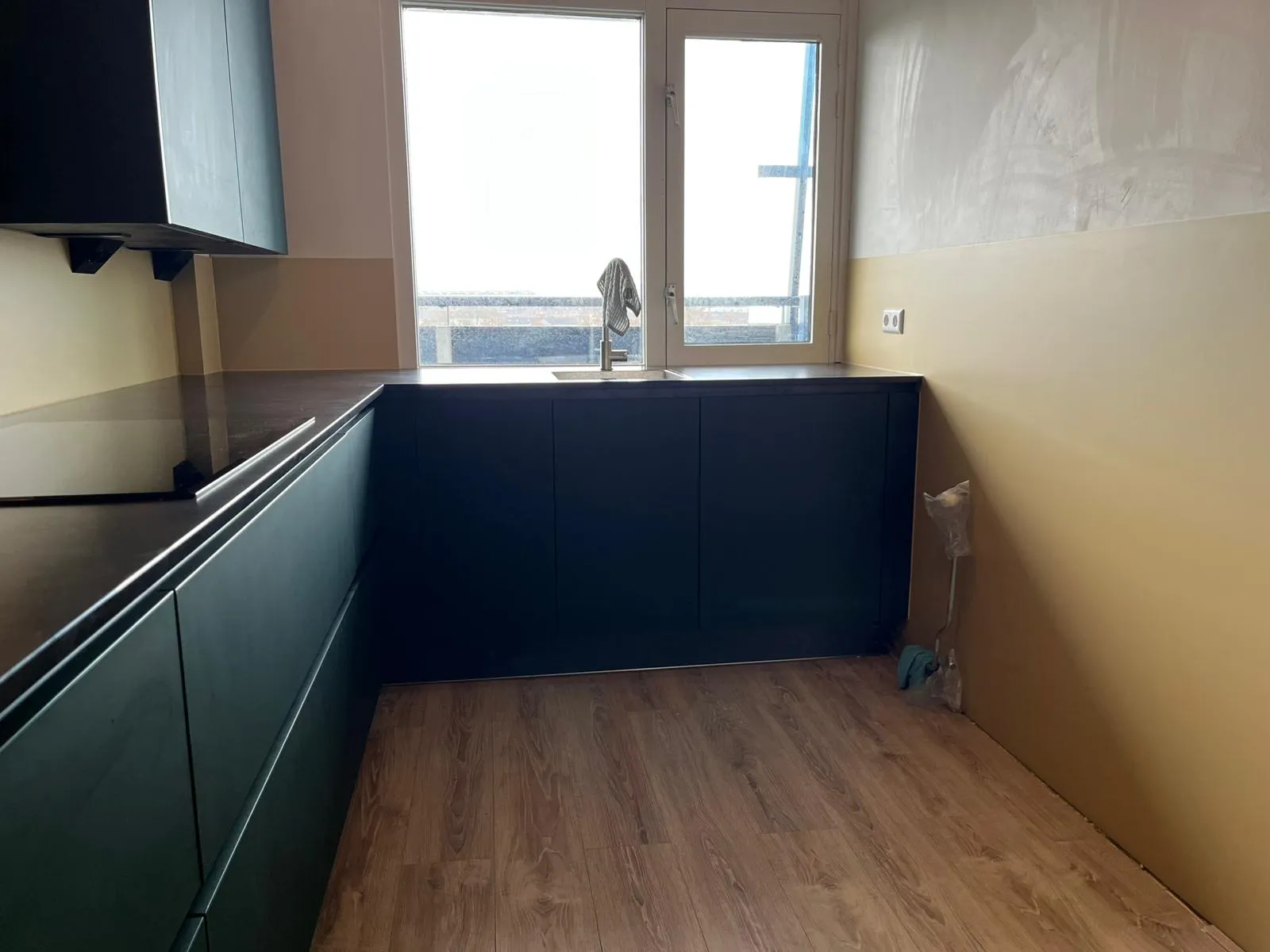 Donkere keuken met een naadloze crèmekleurige rugwand op maat