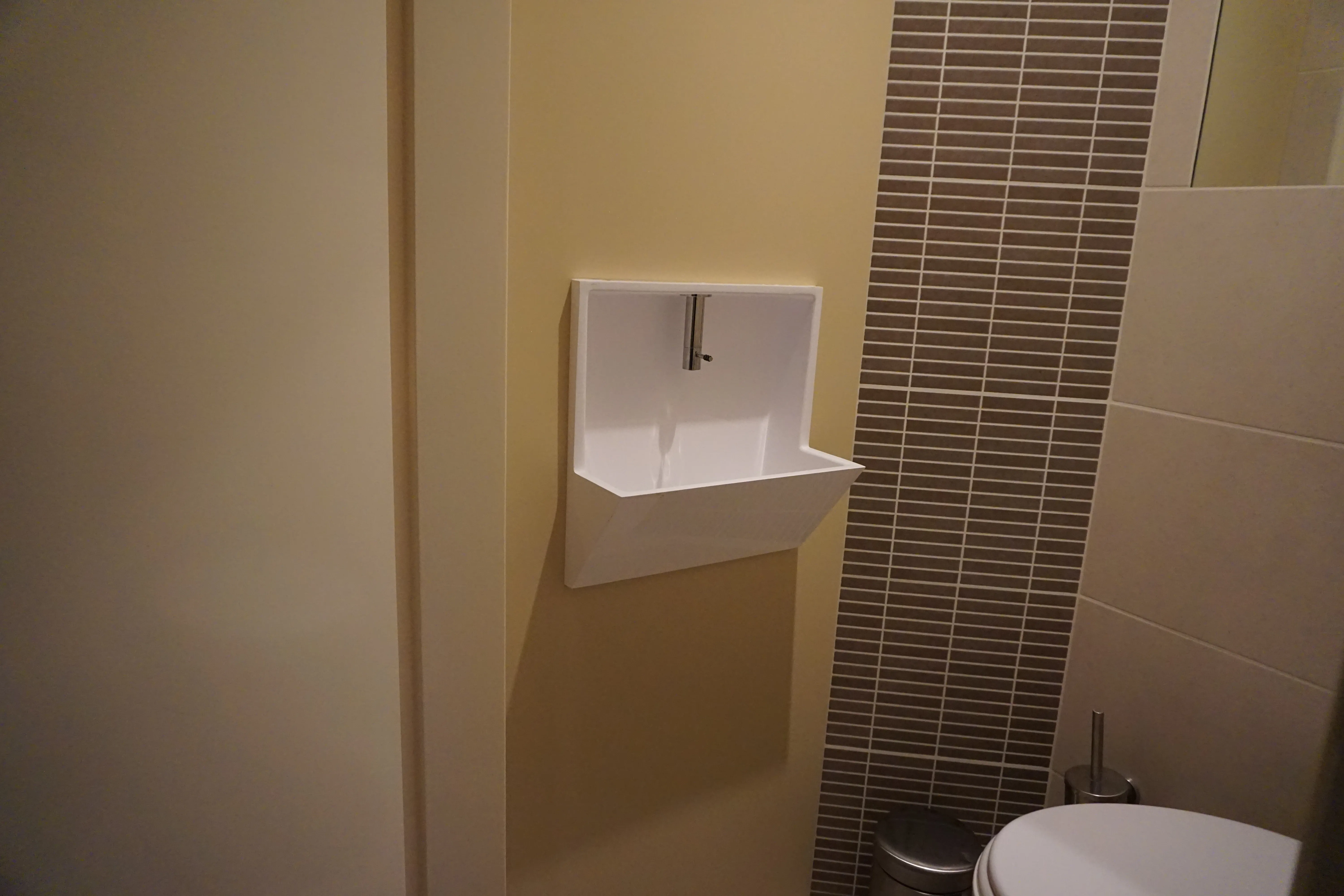 Toilet met een nieuwe wasbak en een naadloze crèmekleurige rugwand op maat