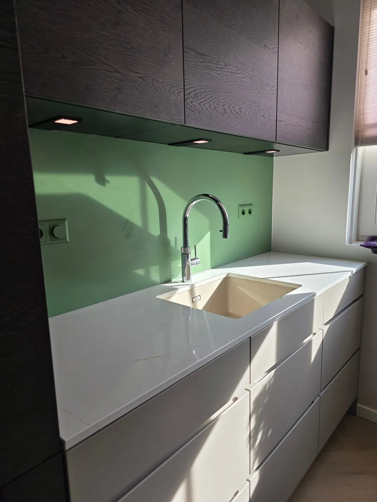 Lichte keuken met donkere houten bovenkasten en een naadloze groene rugwand