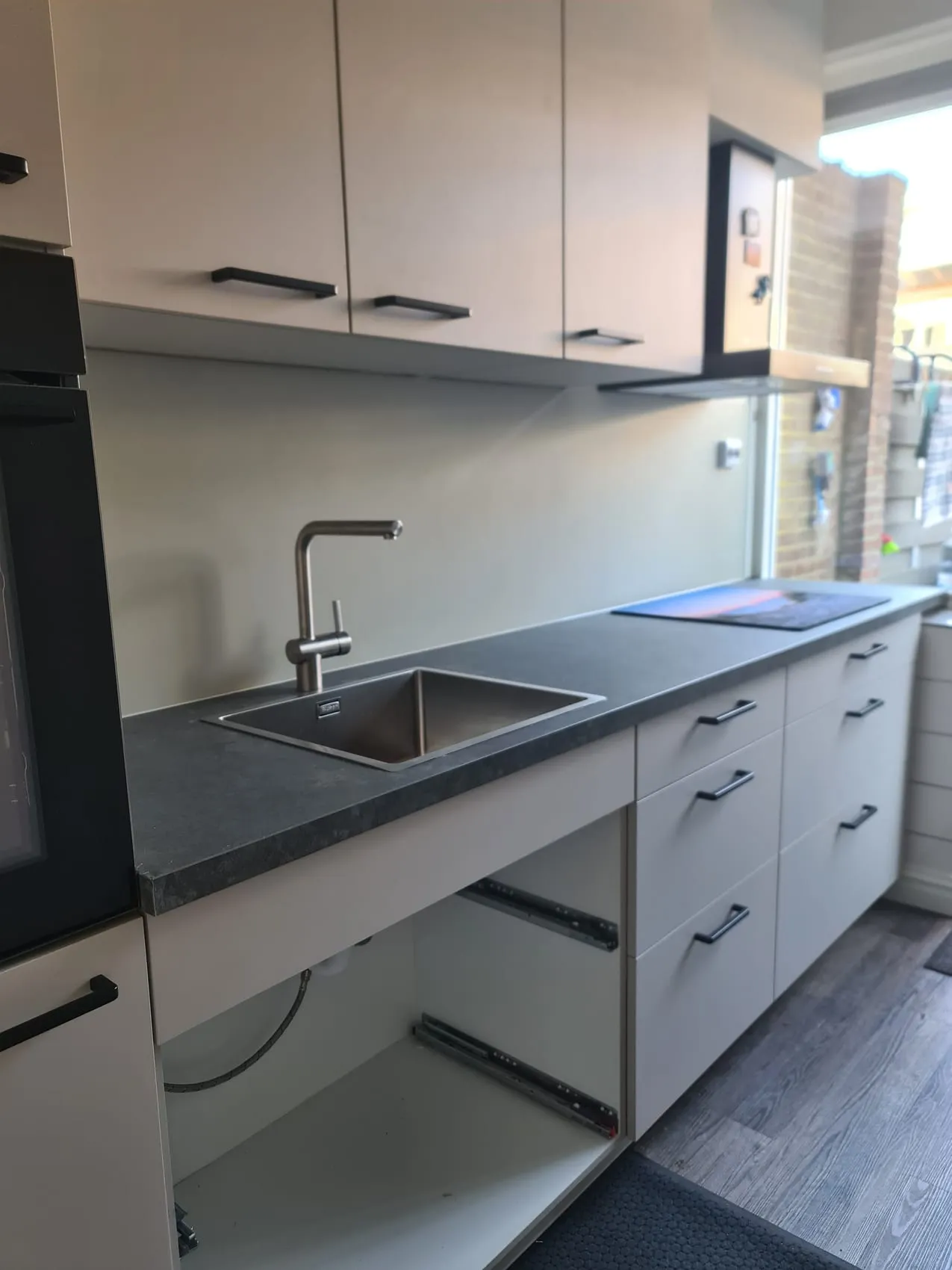 Moderne keuken met een naadloze grijze rugwand in plaats van oude tegels