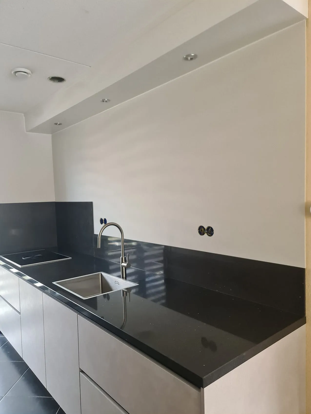 Keuken met zwart werkblad en een naadloze witte rugwand in plaats van een gele muur