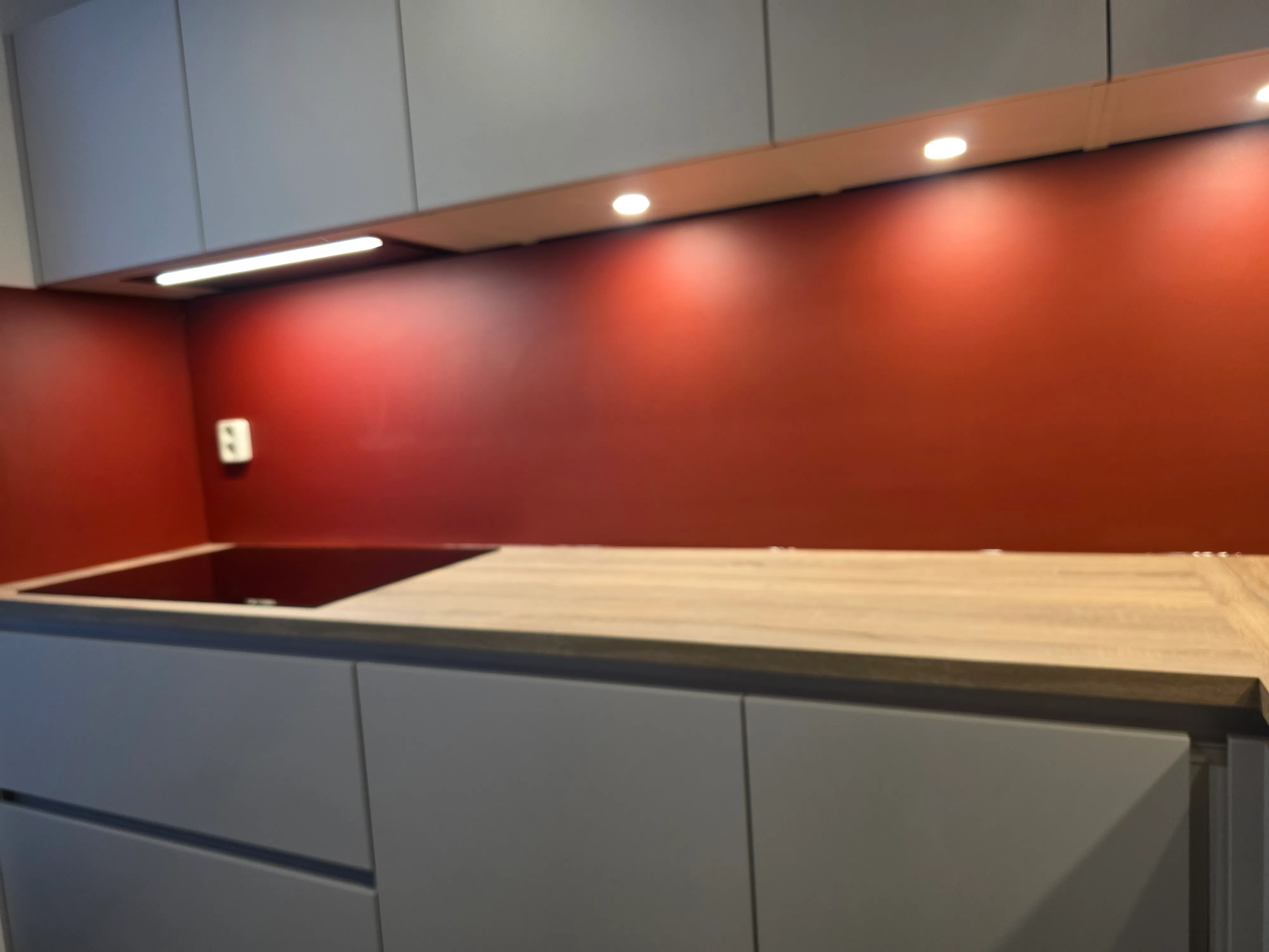 Een rode rugwand voor een lichte keuken met houten werkblad — na de plaatsing
