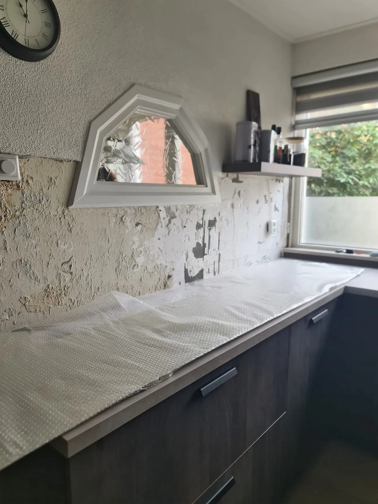 Crèmekleurige rugwand rond een bijzonder hoekig raam — voor de plaatsing