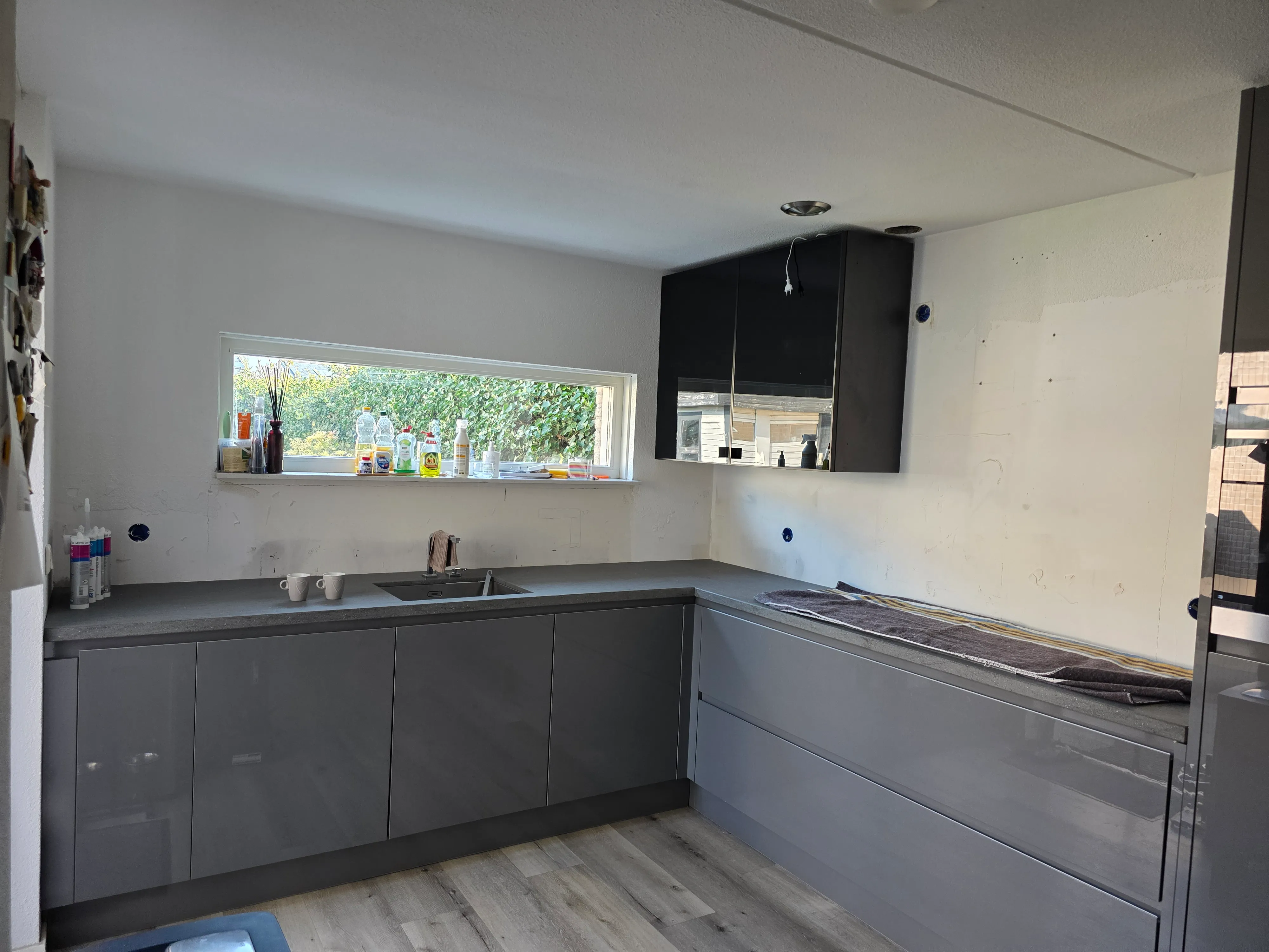 Een grijze keuken met greige Steel Magnetic™ rugwanden — voor de plaatsing