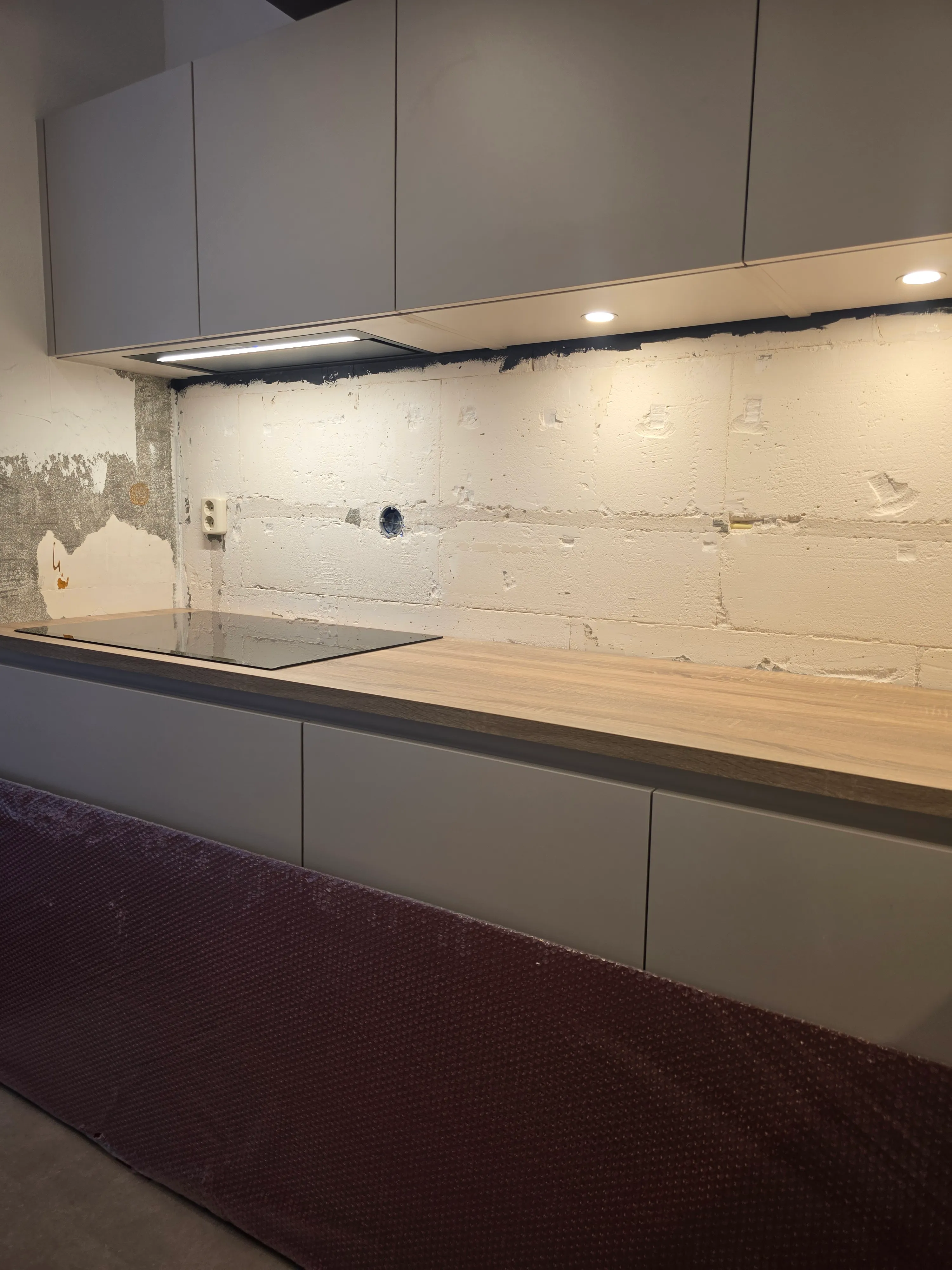 Een rode rugwand voor een lichte keuken met houten werkblad — voor de plaatsing